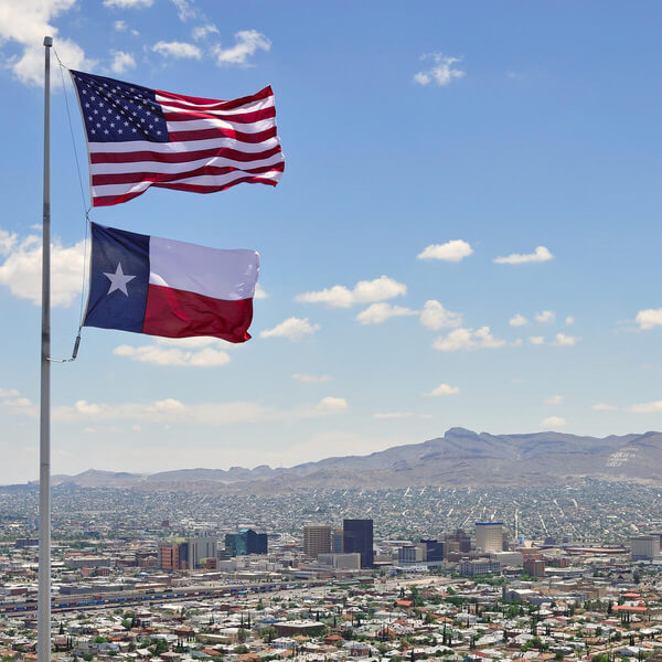 A shot of downtown El Paso, Texas, with the U.S. and Texas flags in the foreground.  Ciudad Juarez and the Juarez Mountains of northern Mexico are visible to the south of the downtown.  This picture was taken from a point just up the hill from El Paso's famous Scenic Drive."